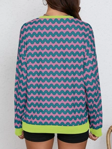 Detail view of pink and teal wavy pattern sweatshirt with green ribbed cuffs on back