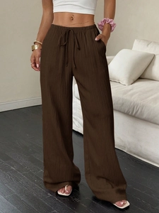 Detalle de pantalones de pernera ancha y cintura alta en tela marrón texturizada