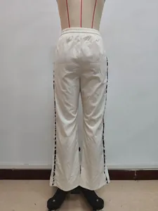 Detail einer weißen Weitbeinhose mit Kordelzug am Bund und geometrischem Seitenstreifen