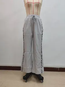 Detail einer hellgrauen weiten Hose mit Kordelzug am Bund und gemustertem Seitenstreifen