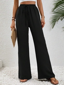 Dettaglio di pantaloni neri a gamba larga con coulisse elastica e tessuto fluido operato