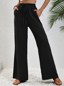 Dettaglio di pantaloni neri a gamba larga con vita alta elastica e coulisse decorativa