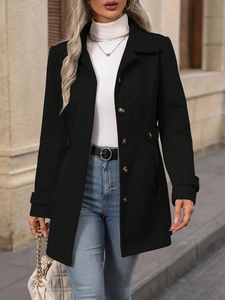 Detail of a black wool coat featuring amber buttons and stylish waist strap accents