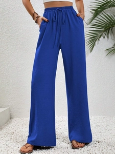 Detail of high waist blue wide leg trousers with drawstring waist and textured fabric