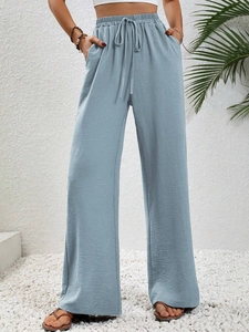 Detail of light blue high-waisted wide-leg trousers with elastic drawstring waist and pockets