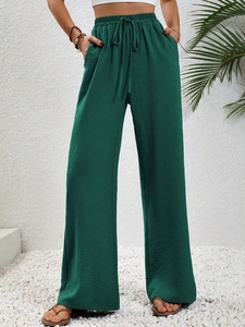 Detail of high-waist dark green wide-leg trousers with elastic drawstring waistband
