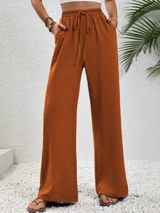Dettaglio dei pantaloni larghi color caramello con vita alta elastica e coulisse