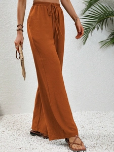 Detail of high waisted wide leg trousers with textured fabric and drawstring waist