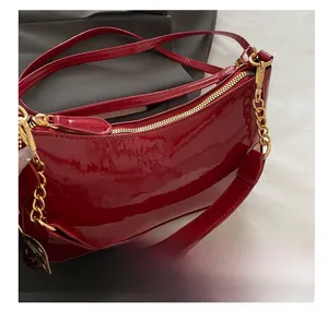 Detail of red patent leather shoulder bag with chain strap and brand logo engraving