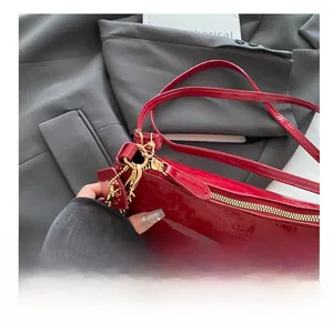 Close-up of smooth golden metal zipper on red patent leather shoulder bag detail