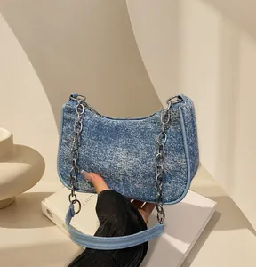 Details der blauen Denim-Textur mit silberner Metallkette an der Unterarmtasche