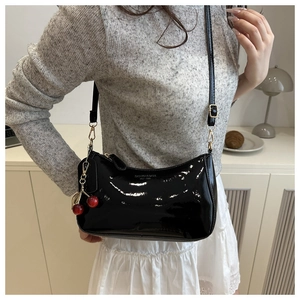 Sac sous le bras noir brillant avec détail de cerise dans un décor intérieur élégant