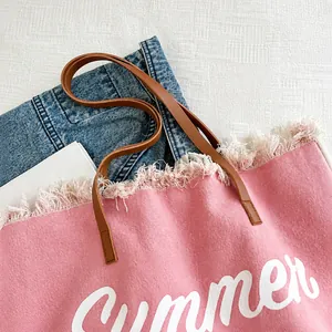 Detail van roze canvas shopper met franjes, lederen handvaten en Summer-print