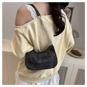 Détail du sac sous le bras en denim noir avec strass argentés et bandoulière chaîne