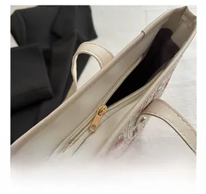 Detail of top gold metal zipper closure on floral tweed tote bag with PU trim
