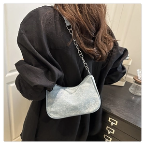 Détail du sac hobo bleu clair pailleté avec bandoulière chaîne porté à l'épaule