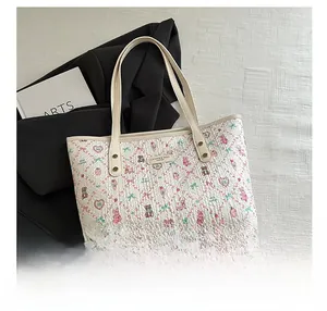 Detail of floral bear print on beige leather tote bag with branded metal logo plate