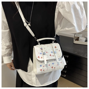 Detail der weißen Umhängetasche mit niedlichen Cartoon-Hunden und Kirschmotiven