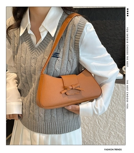 Sac à bandoulière caramel avec nœud décoratif porté par un mannequin en chemise blanche