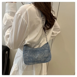 Détail du sac sous l'aisselle en denim bleu avec chaîne argentée et texture pailletée
