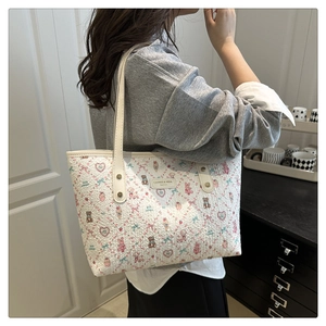 Detailed view of cream tote bag with pink cartoon patterns on textured PU leather