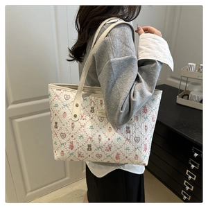 Detail showing white cartoon print tote bag with bear patterns on model's shoulder