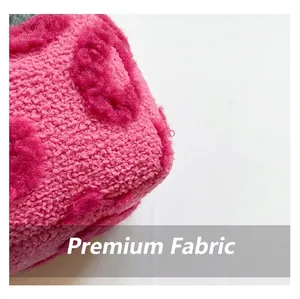 Close-up of soft pink plush fabric with embossed heart patterns and textured faux fur