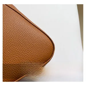 Détail macro de la texture cuir grainé marron caramel et des finitions de couture