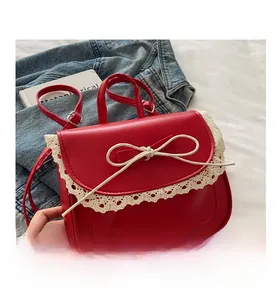 Detail view of red small square bag with lace trim and bow on a white soft surface