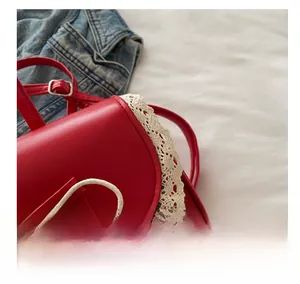 Close-up of red leather handbag featuring white lace edges and bow detail