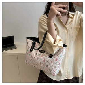 Detail of white tote bag with embossed bear and heart patterns and black leather handles
