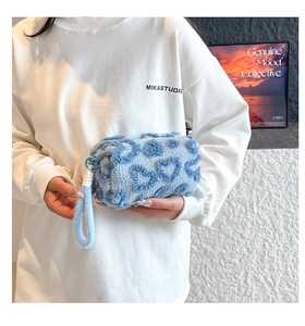 Close-up of light blue plush handbag featuring heart textures and soft carrying handle