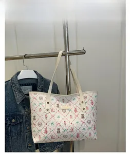 Detail of beige tote bag with embossed cartoon prints and golden logo on a display stand