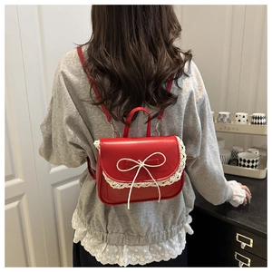 Dettaglio mini zaino rosso in ecopelle con bordo in pizzo bianco e decoro a fiocco