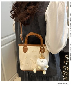 Détail du sac seau crème avec gaufrage dessin animé et breloque en peluche blanche