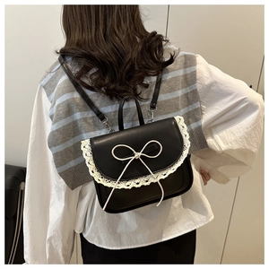 Dettaglio mini zaino nero in pelle con pizzo e fiocco bianco sulla schiena della modella