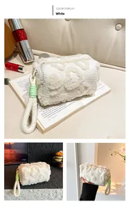 Detail of white plush storage bag with tufted pattern and green stitching on the handle