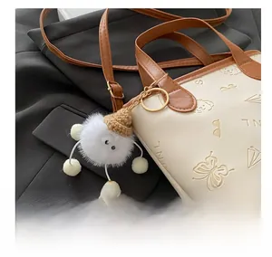 Détails du sac seau en cuir crème avec papillons embossés et breloque pelucheuse