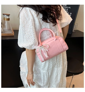 Détail du sac Boston rose en similicuir avec nœud en dentelle perlée et relief