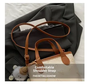 Détail de la bandoulière réglable et du sac seau crème embossé sur un blazer gris