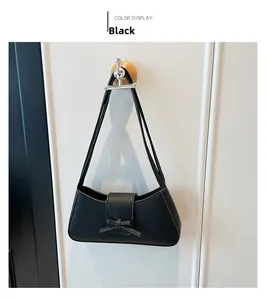 Détail du sac sous le bras noir minimaliste avec texture grainée et décoration de nœud