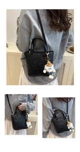 Détail du sac seau noir avec gaufrage SMNL et accessoire de charme en peluche