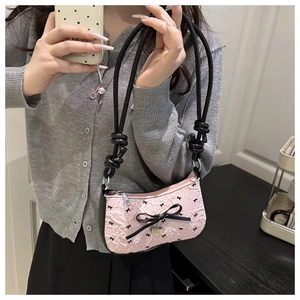 Detailed shot of pink pleated crescent bag with black bow embroidery and heart pendant