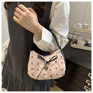 Detail of pink pleated fabric handbag with black bow embroidery and heart pendant