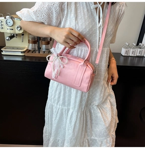 Sac Boston rose avec nœud en perles et charme en dentelle montré en scène de style de vie