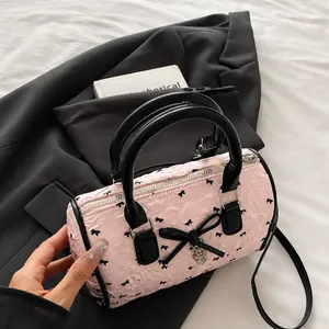 Detailed view of pink pleated barrel bag with black bow patterns and comfortable handle