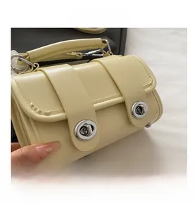 Détails du sac Boston crème avec fermoirs rotatifs argentés et poignées supérieures