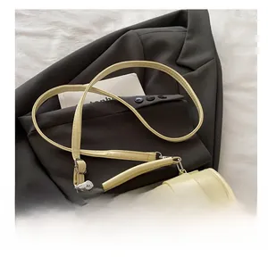 Détail d'un sac Boston jaune crème avec breloque cœur en perles et dentelle sur blazer gris