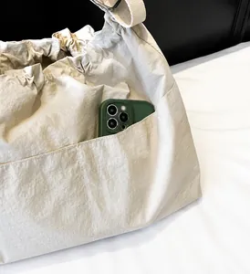 Detail of nylon bucket bag showing functional side pocket holding a large smartphone