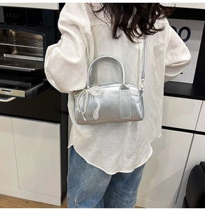 Sac Boston argenté avec breloque nœud en dentelle et perles porté par un mannequin chic
